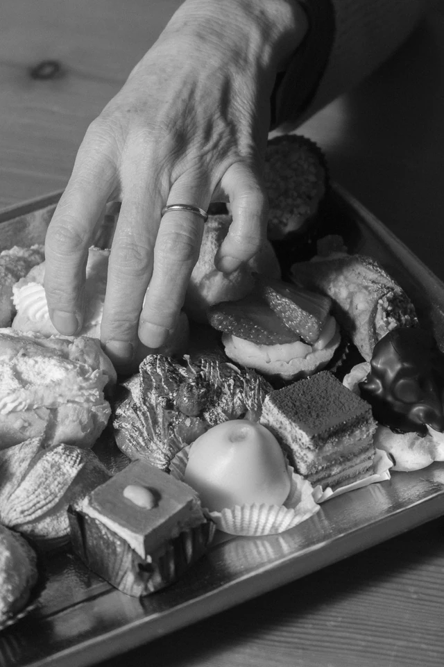 A hand wearing a ring reaches for pastries on a tray in Rome